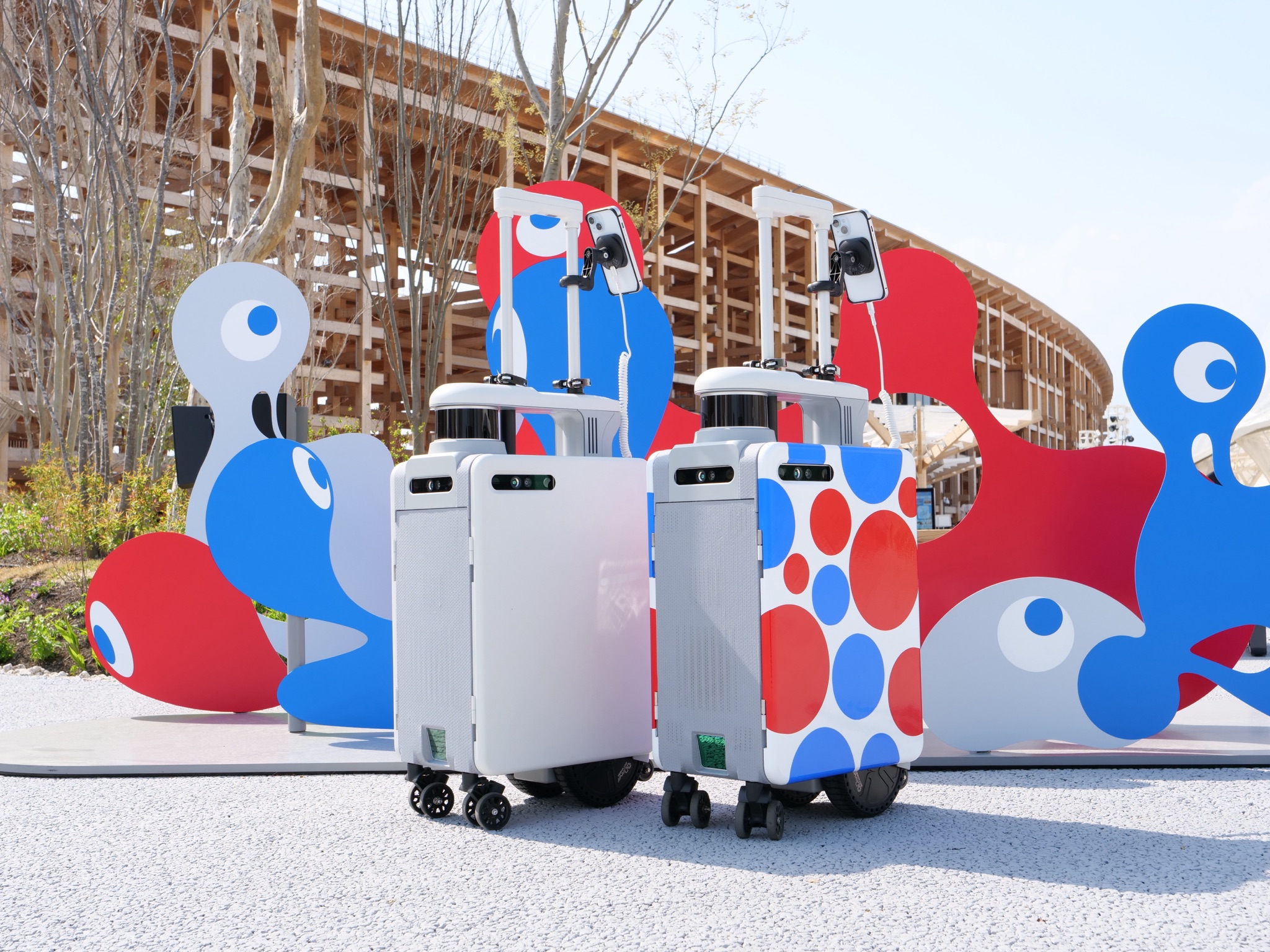 大阪・関西万博会場のオブジェ前に並ぶ2台のAIスーツケース